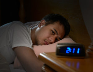man looking at alarm clock unable to sleep