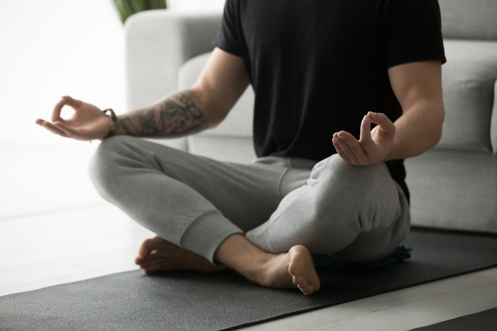 Tattooed Man Meditating At Home