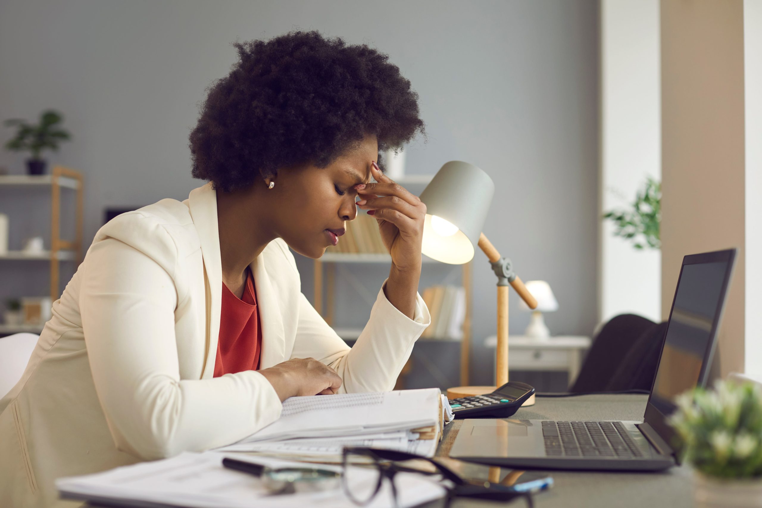 woman with burnout sat on desk with head in hand