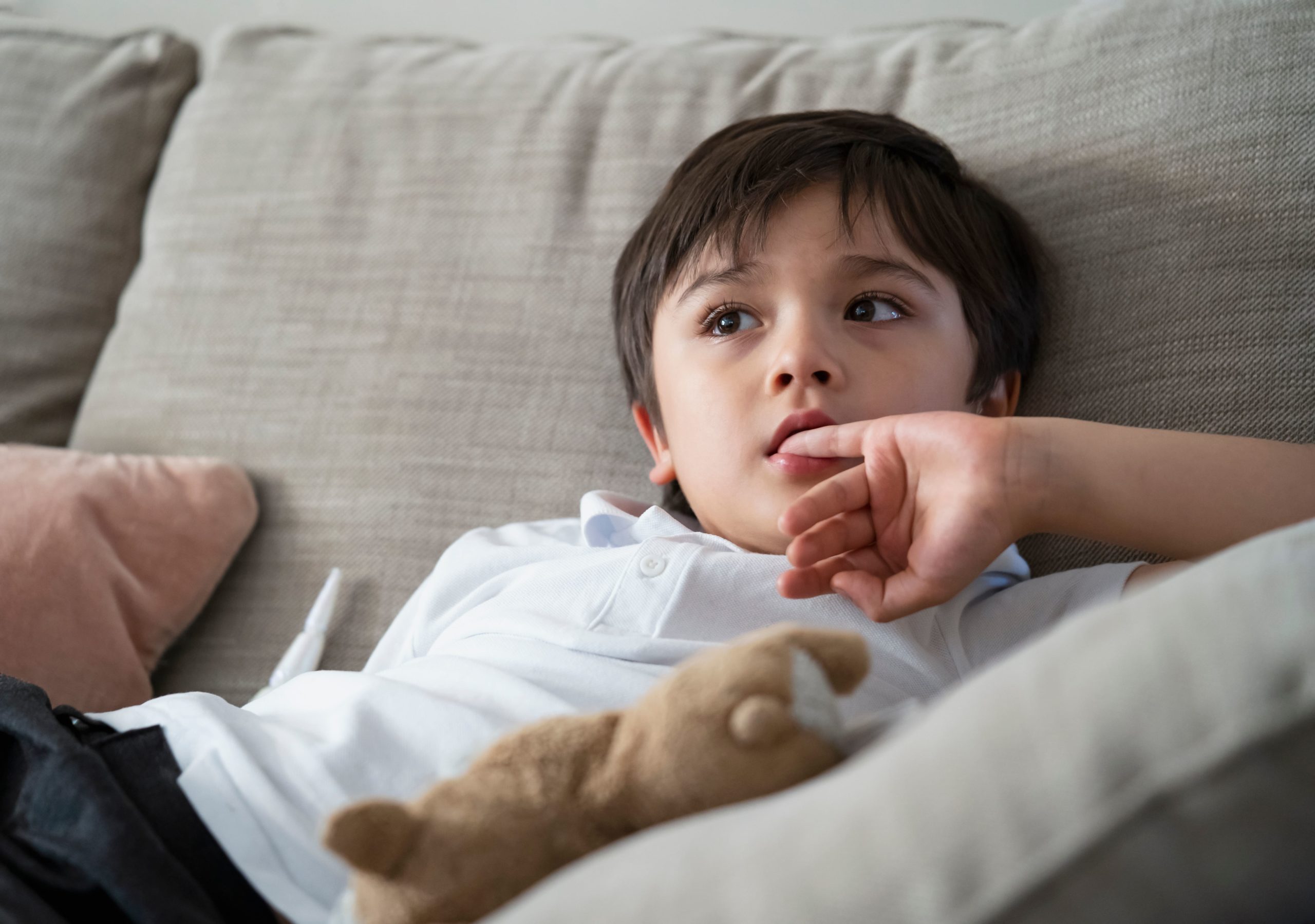 child with anxiety sat on sofa biting nails