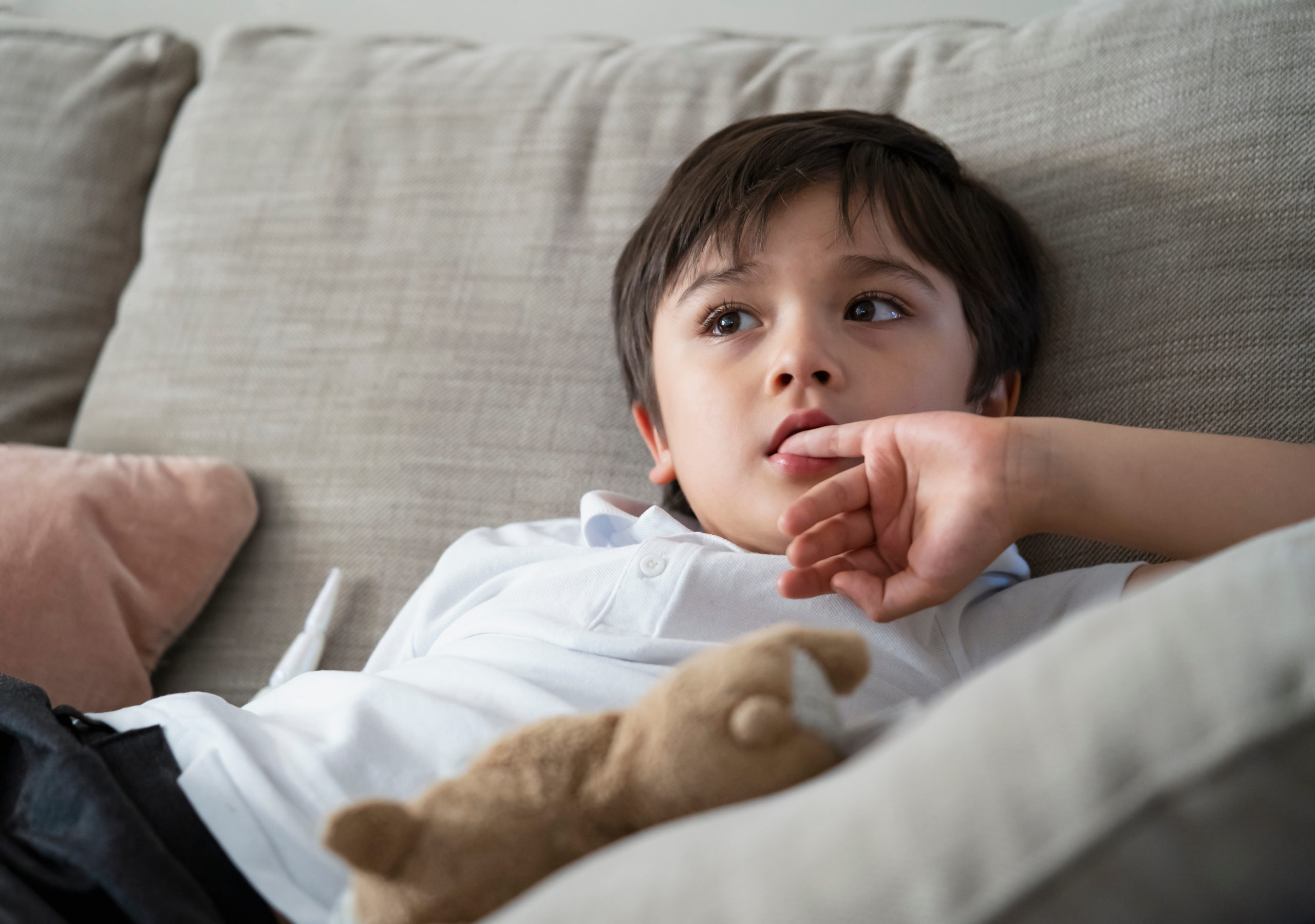 child with anxiety sat on sofa biting nails