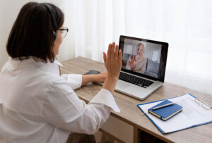 online therapist smiling and waving to client through laptop screen