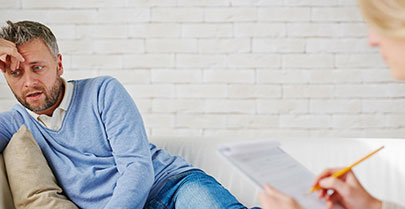 Man sat on sofa talking to therapist making notes