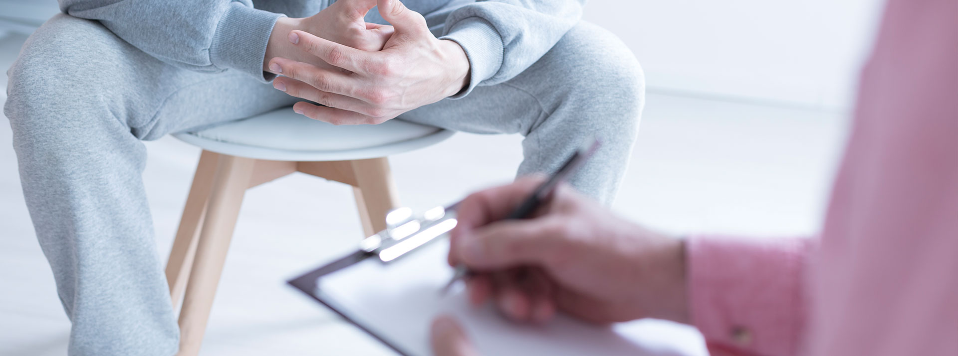 Therapist making notes while person holds hands together
