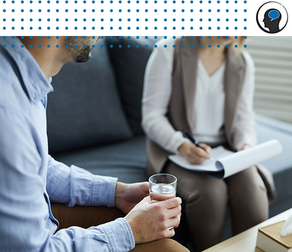 Man holding drink while therapist makes notes during session