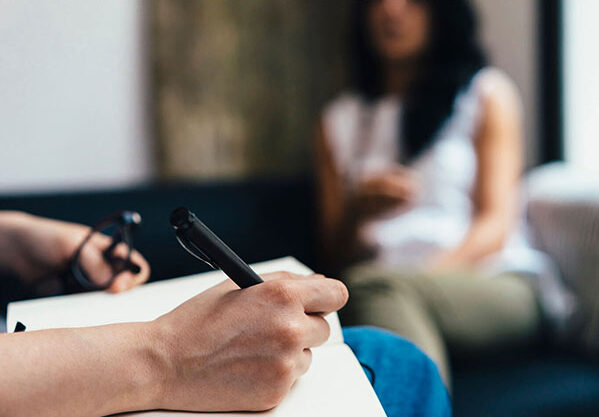 counsellor in Newcastle writing down notes while speaking to client