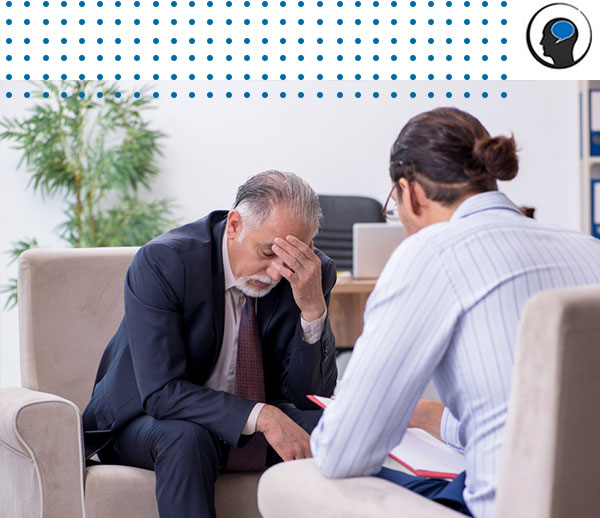 Man with head in hands speaking to therapist