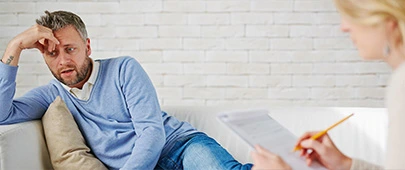 Man sat on sofa talking to therapist making notes