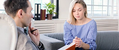 Woman holding hands together while therapist is listening on