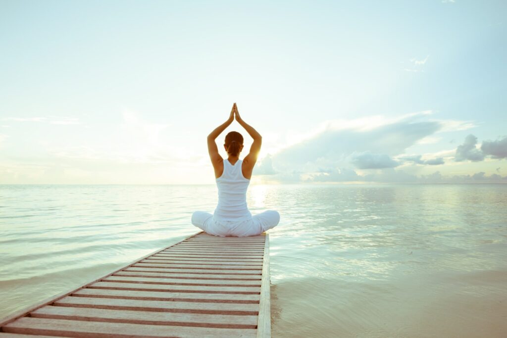 Woman practising meditation on edge of pier