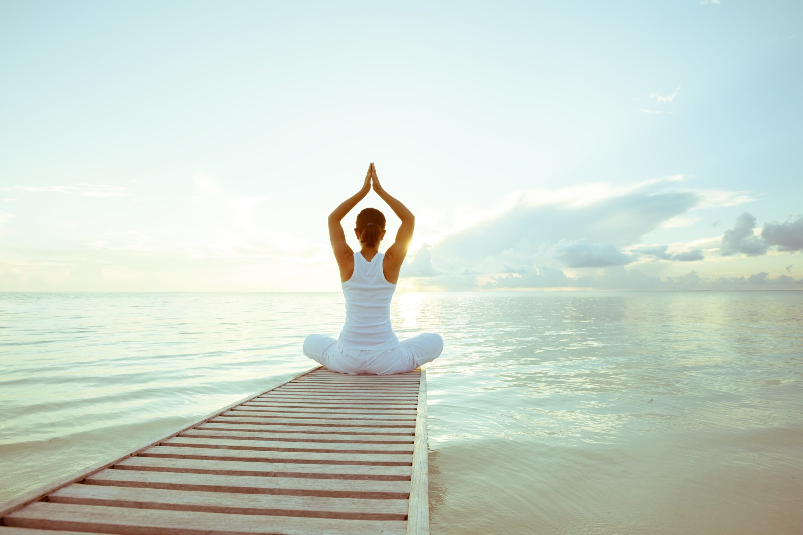 Woman practising meditation on edge of pier